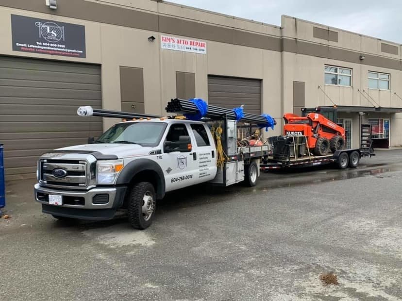 LS Fencing service truck towing a trailer with a Kubota skid steer used for commercial snow removal in the Fraser Valley
