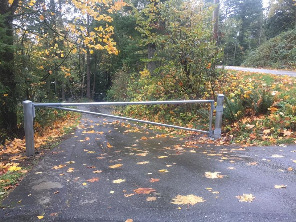 Galvanized barrier gate across a wooded access lane — photograph supplied by LS Fencing & Metal Work